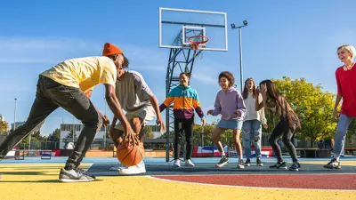 Seven people playing basketball outisde on a court