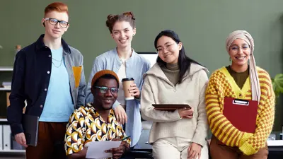 Five students smiling at the camera situated in an office